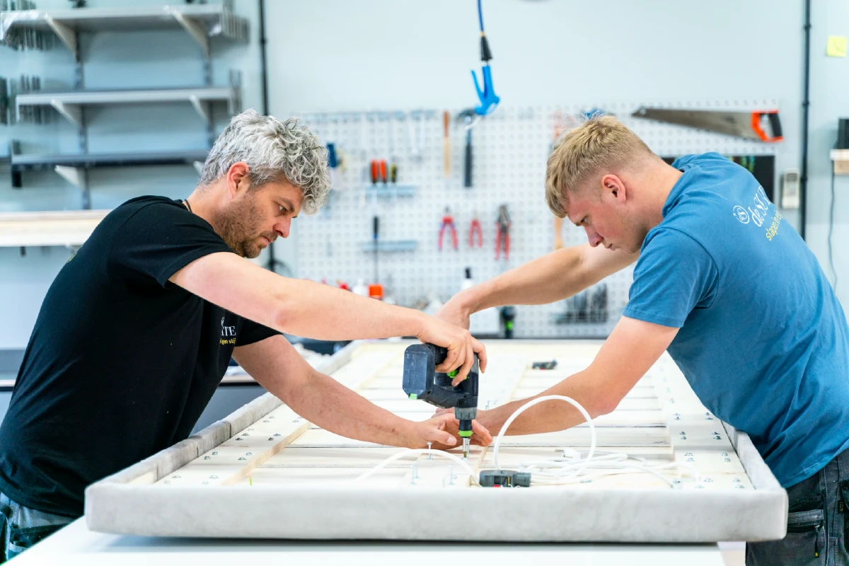 Meubelmakers in werkplaats bezig met bed