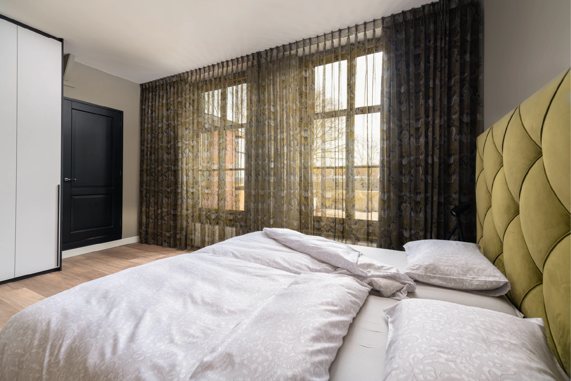 Slaapkamer met groene gordijnen en vitrage